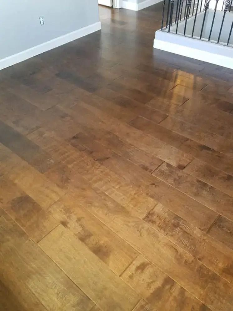 Empty room with warm wood flooring and a staircase railing in the corner