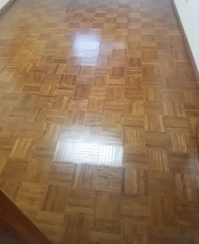 Empty hallway with glossy parquet wood floor and white walls reflected in the surface.