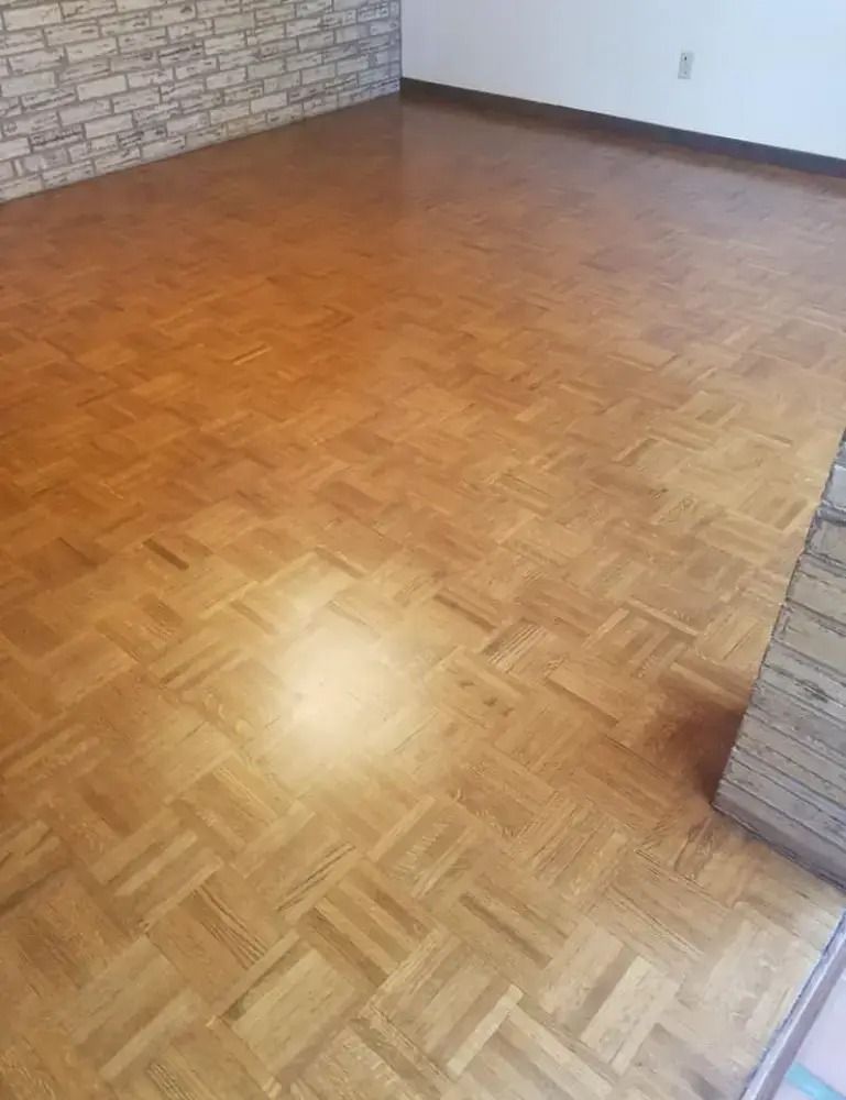 Empty room with glossy parquet wood floor and partial stone walls