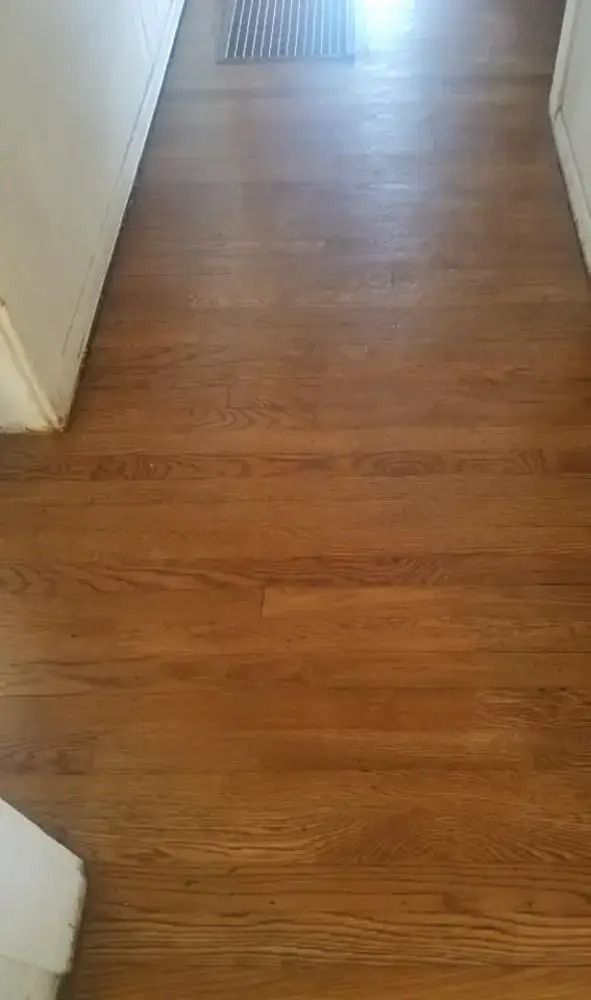 Wooden hallway floor with white walls and bright light at the far end