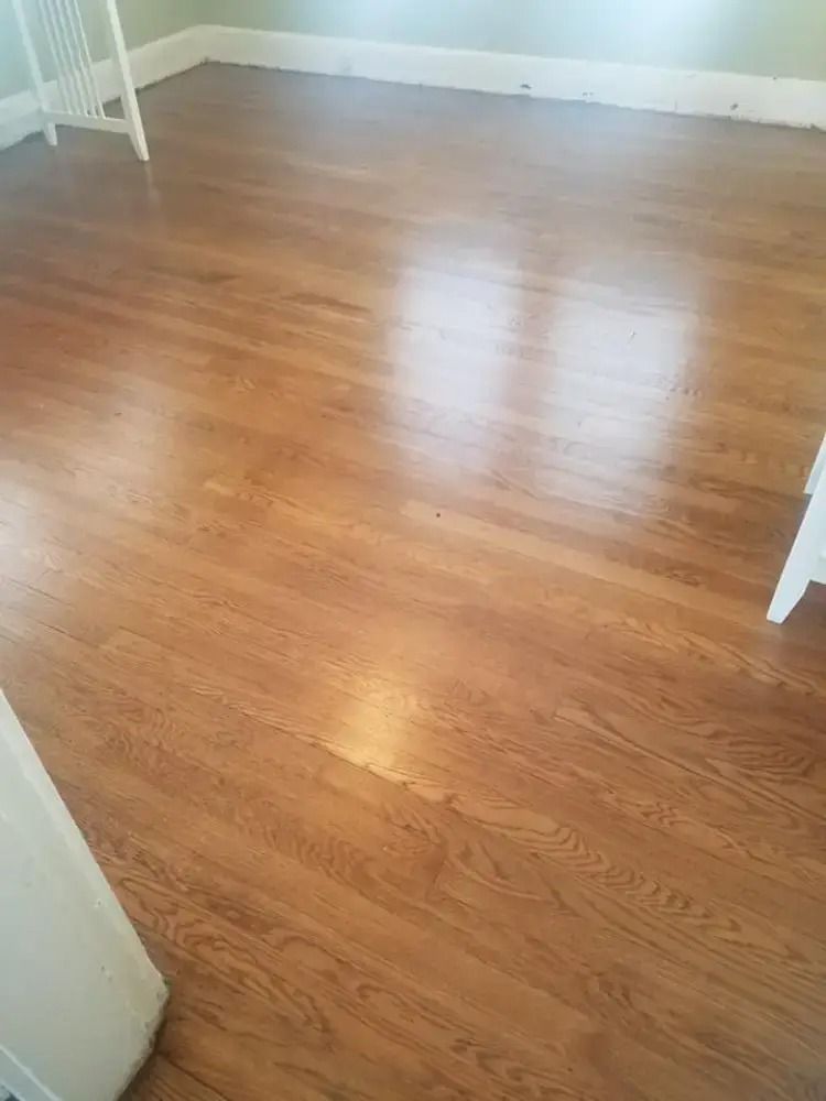 Empty room with glossy light-brown hardwood floor and white walls, viewed from a doorway.