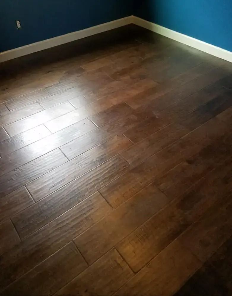 Empty room corner with dark wood flooring, blue walls, and white baseboards
