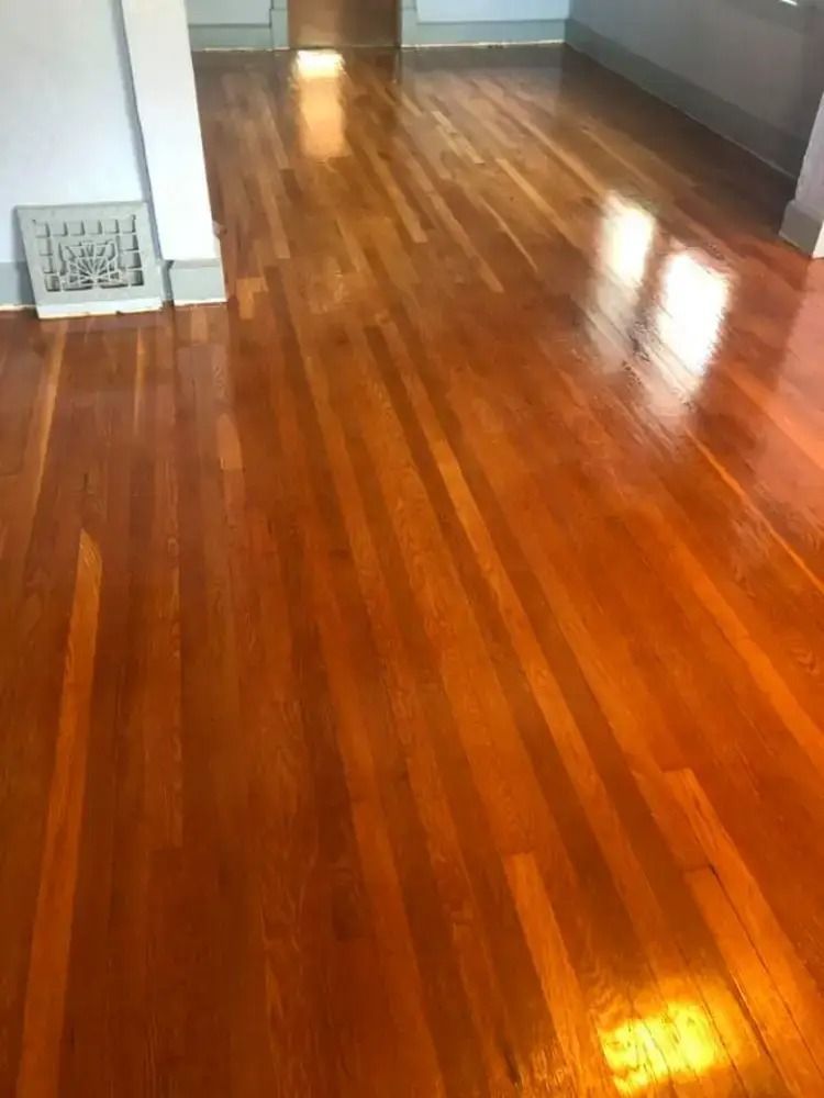 Empty polished hardwood floor in a room, with light reflecting near the bottom right.