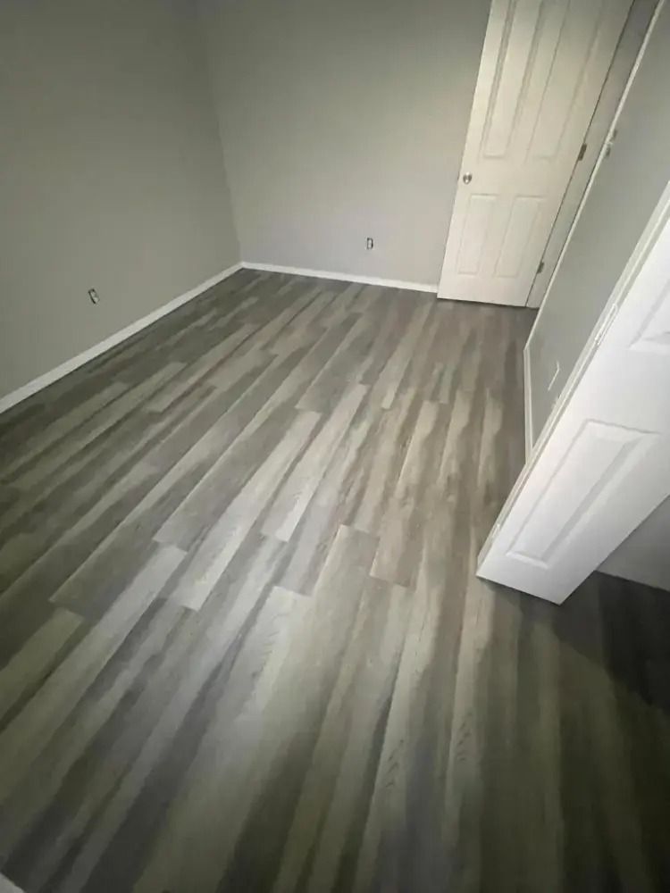 Empty room with gray wood-look flooring, white closet door, and light gray walls