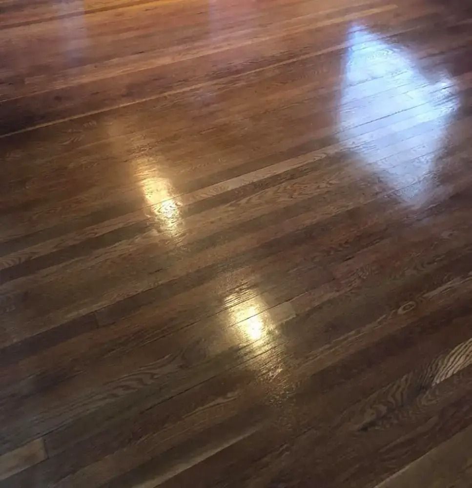 Polished hardwood floor with bright window reflections