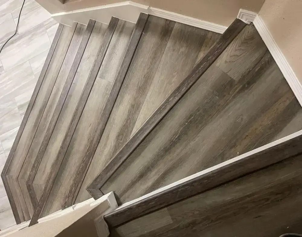 Curved staircase with gray wooden steps and white railings viewed from above