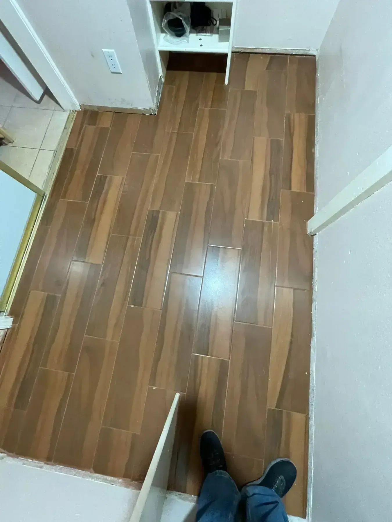 Narrow kitchen hallway with wood-look flooring and a partially open cabinet, viewed from above.