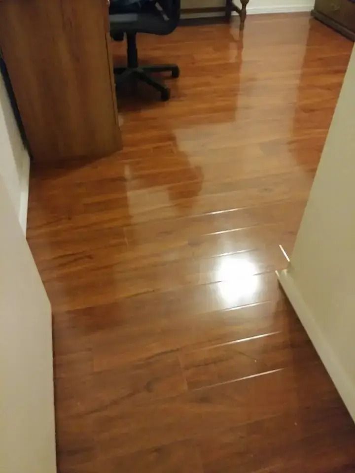 Shiny hardwood hallway floor with a doorway and office chair in the background