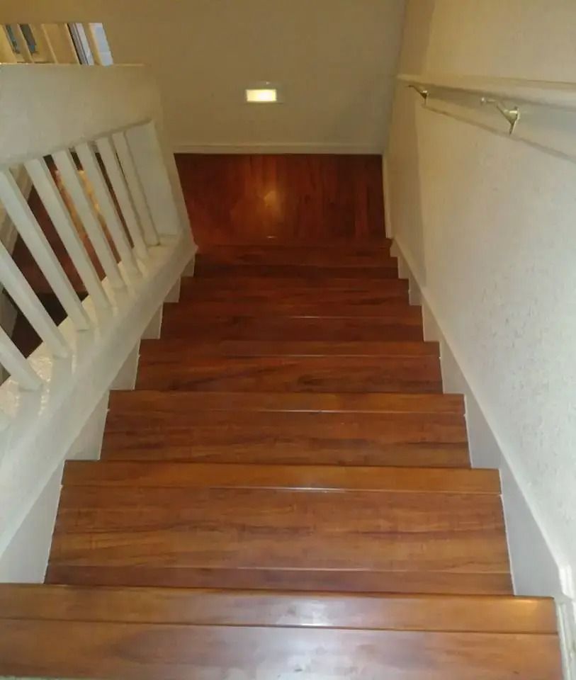 Wooden staircase with white walls and railing, viewed from the top looking down.