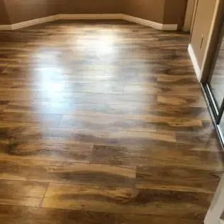 Empty room with wood-look flooring and brown walls, lit by bright window light