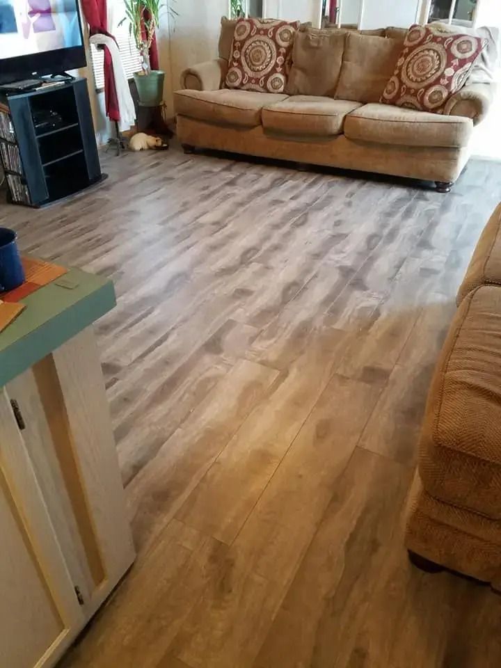 Living room with tan sofas, patterned cushions, and wood-look flooring