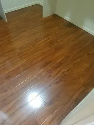 Empty room with polished wood floor and white walls, lit by a bright reflection.