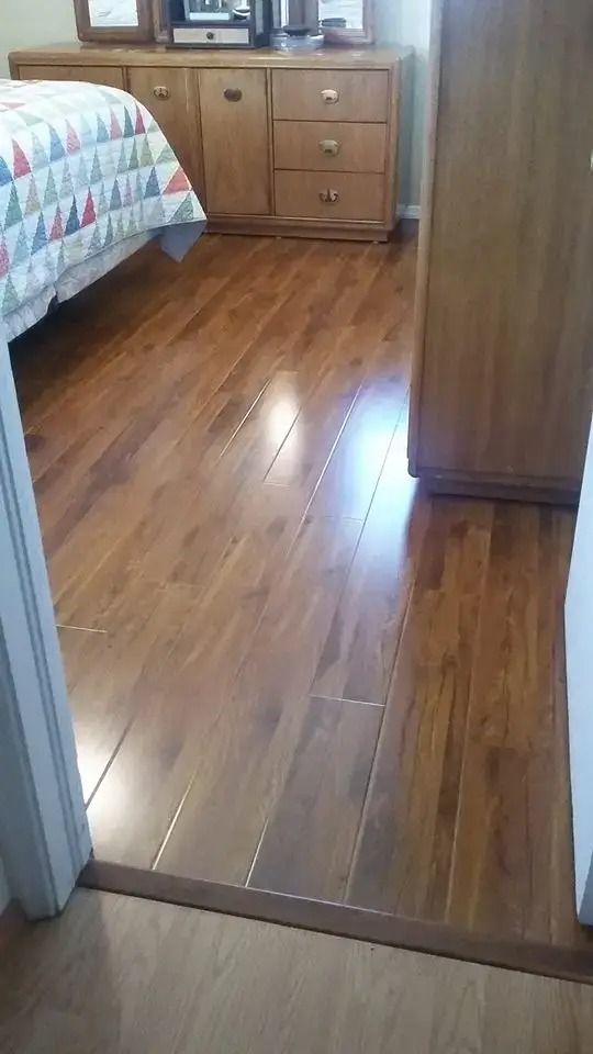 Bedroom with hardwood floor, bed at left, dresser in back, and a doorway in the foreground.