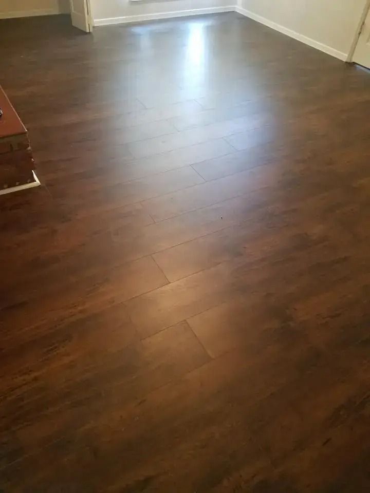 Empty room with dark wood flooring and sunlight reflecting near the far wall.