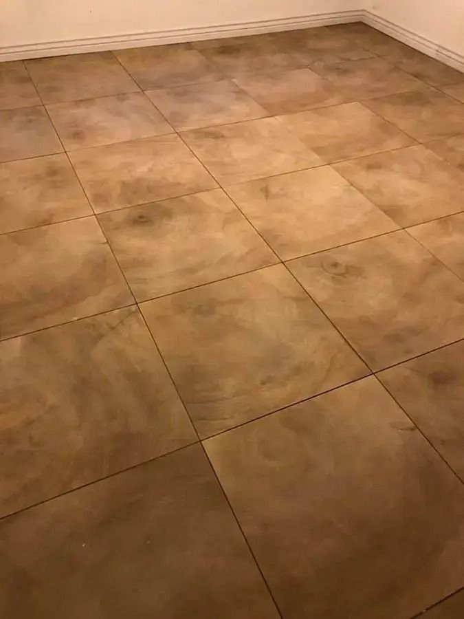 Beige tiled floor with square tiles and a white wall in the corner.