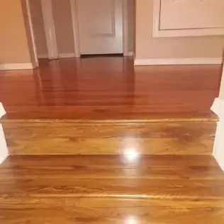 Wooden step leading up to a polished hardwood floor in a hallway