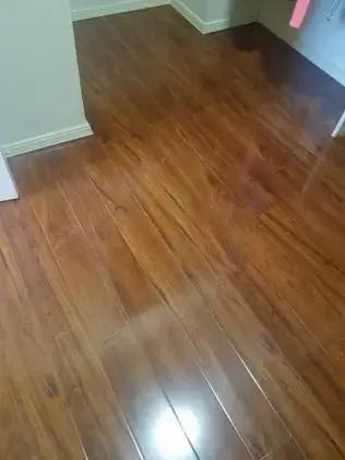 Empty room with glossy brown wood flooring and white walls, viewed from a doorway.
