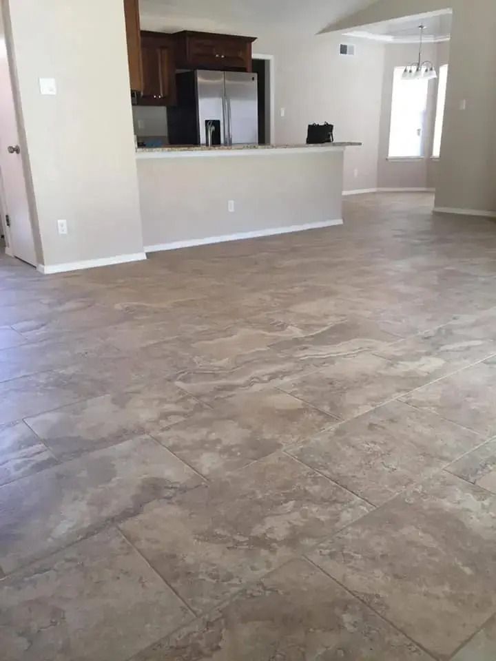 Empty living room with tiled floor and kitchen pass-through counter in the background
