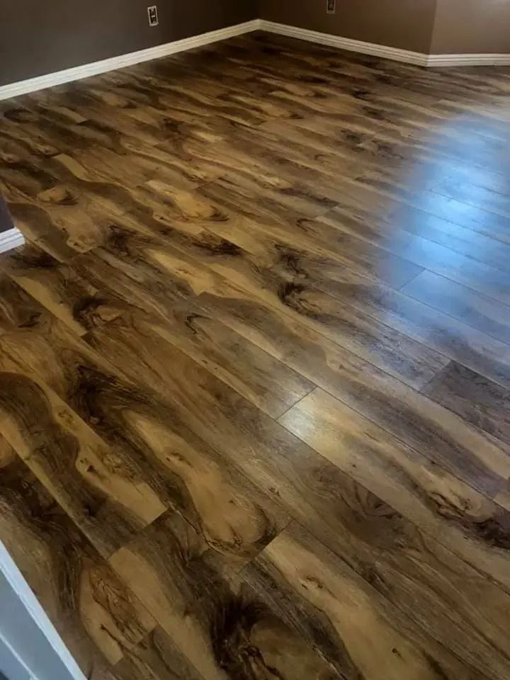 Empty room with glossy wood-look flooring and brown walls, lit by natural light.