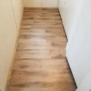 Narrow hallway with wood-look flooring and white walls