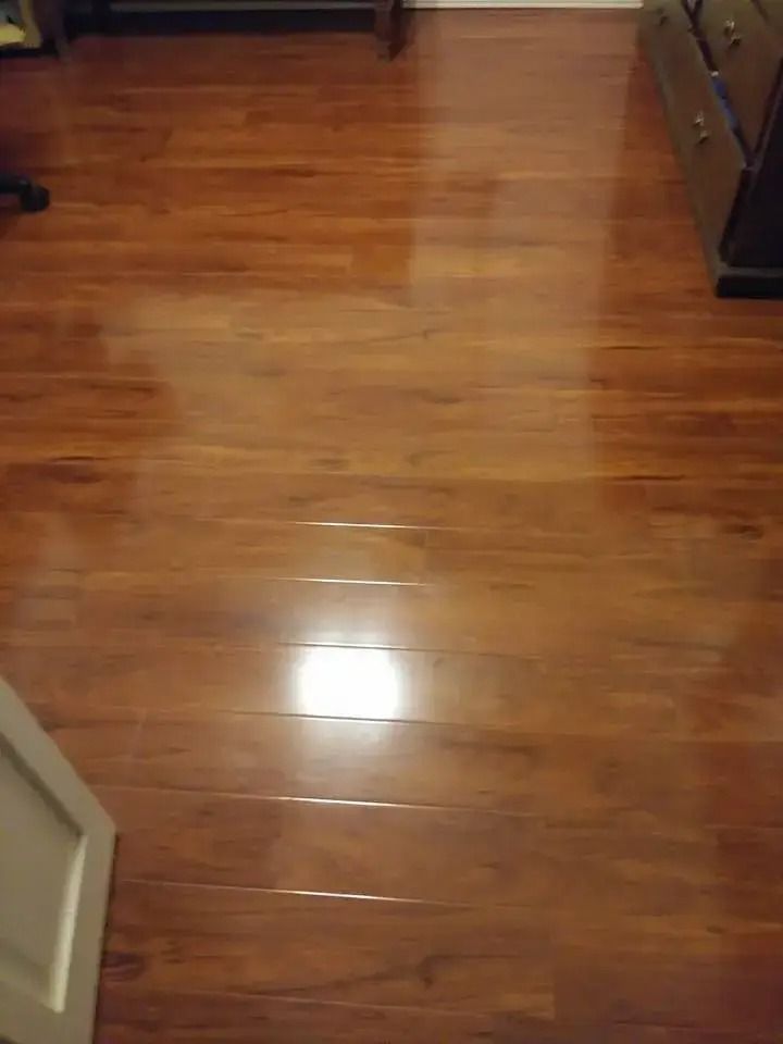 Wooden hardwood floor with light reflection, seen from a doorway in a room.