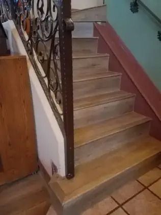 Indoor stairway with beige steps, brown railing, and tiled floor at the bottom