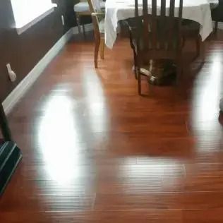 Wooden dining room floor with table and chairs, bright light reflecting on the floor