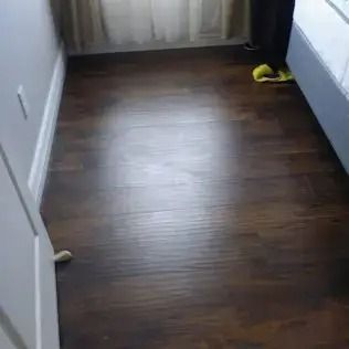 Empty room with dark wood floor, white walls, and a yellow shoe near the back wall