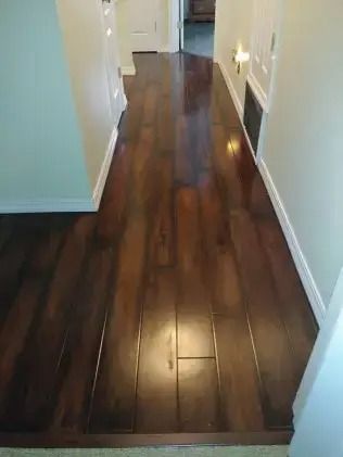 Narrow hallway with dark hardwood floors, white walls, and soft wall lighting.