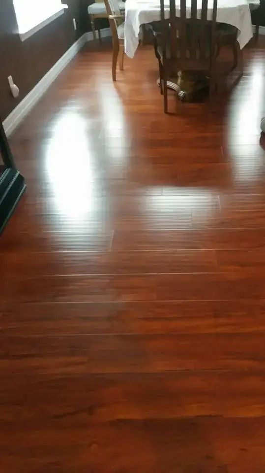 Polished hardwood floor in a dining room with chairs and a table at the far end.
