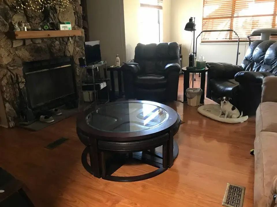 Living room with leather chairs, a round coffee table, and a stone fireplace