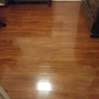 Empty room with glossy wooden floor and a bright light reflection in the center