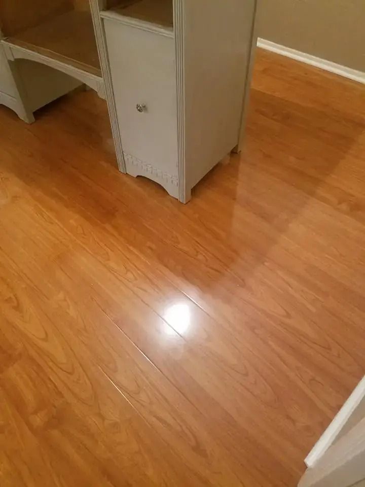 Empty wood-floored room with a gray cabinet and a bright light reflection on the floor.