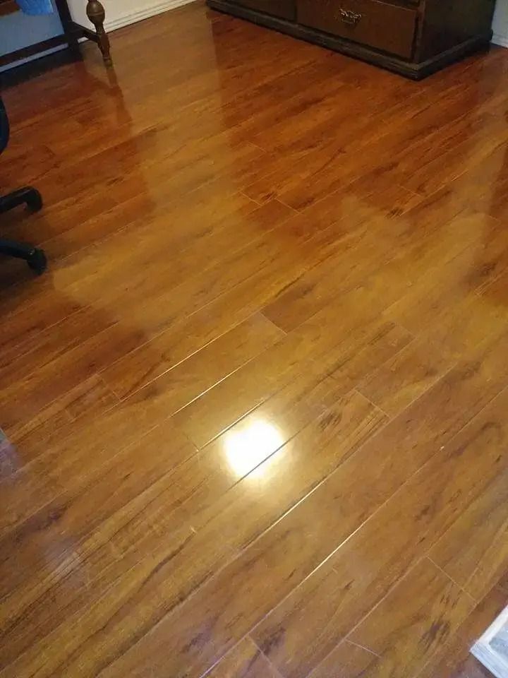 Shiny hardwood floor in a room with a wooden cabinet and office chair visible at the edges.