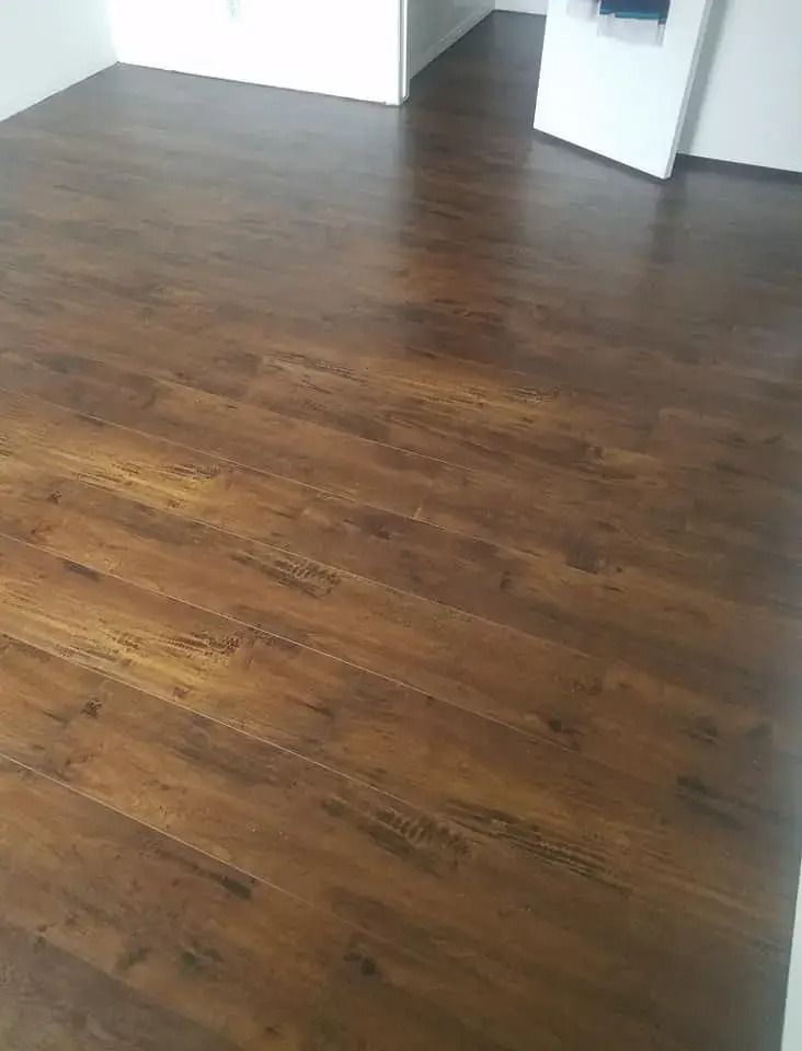 Empty room with dark wood flooring and white walls, viewed toward an open doorway.