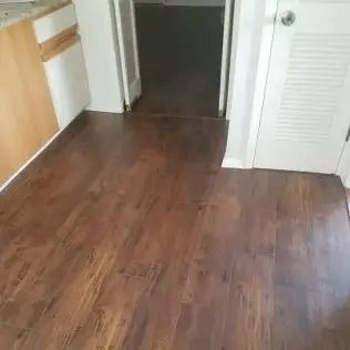 Empty hallway with brown wood flooring and white doors.