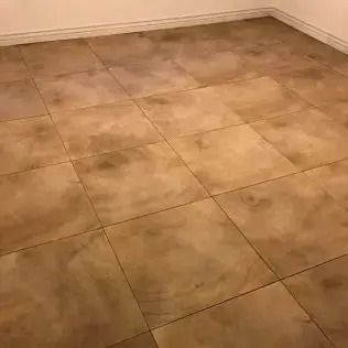 Empty tan tiled floor in a corner with beige walls.
