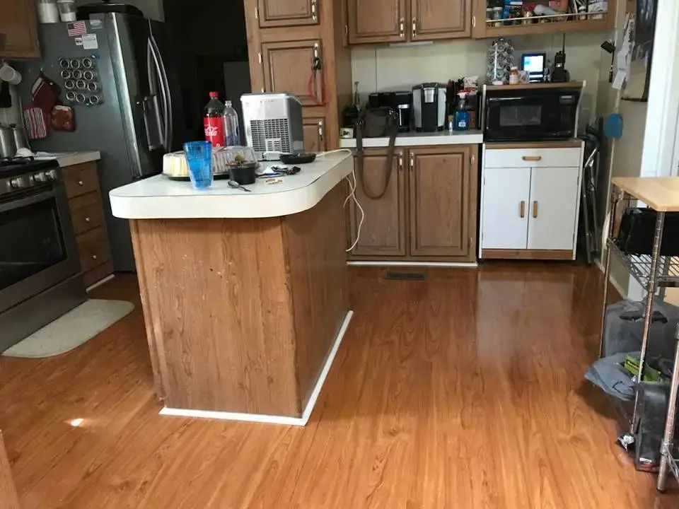 Kitchen with wooden island, brown cabinets, white appliances, and hardwood floors