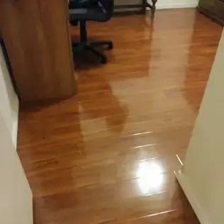 Glossy hardwood floor in an office hallway beside a wooden desk and chair