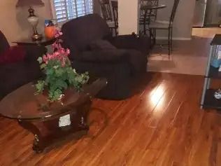 Living room with dark armchairs, wooden coffee table with flowers, and hardwood floor
