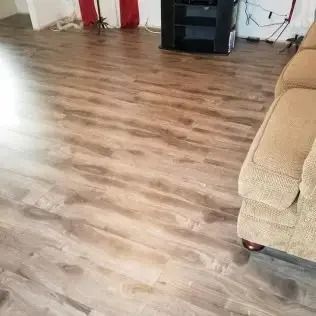 Living room with wood-look flooring, beige sofa, and black storage cabinet near the wall.