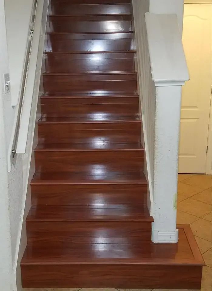 Wooden staircase with polished dark steps and white railings leading to a hallway