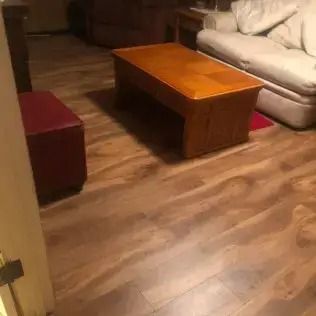 Living room with a wooden coffee table, beige sofa, and burgundy ottoman on wood flooring