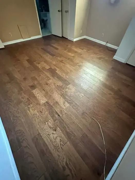 Empty room with wood flooring, beige walls, and an open doorway.