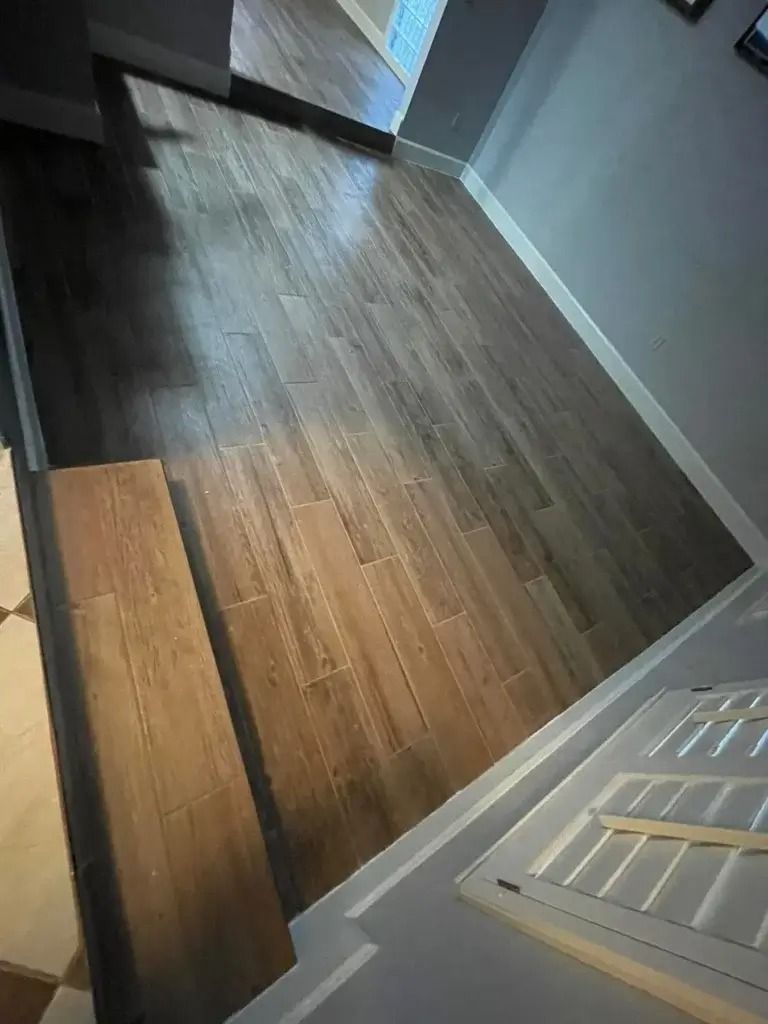 Narrow hallway with dark wood flooring, light gray walls, and white trim, viewed from a doorway.