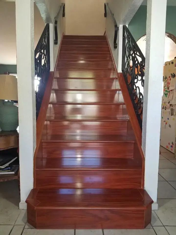 Polished wooden staircase with wrought-iron railings leading to an upper floor indoors