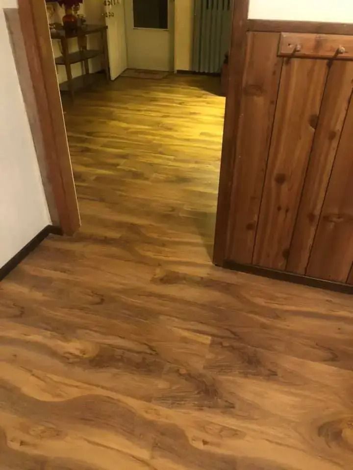 Wooden hallway with a warm-lit room in the background and a wood cabinet on the right.