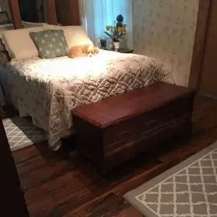 Cozy bedroom with a bed, wooden bench, small lamp, and patterned rugs in warm lighting