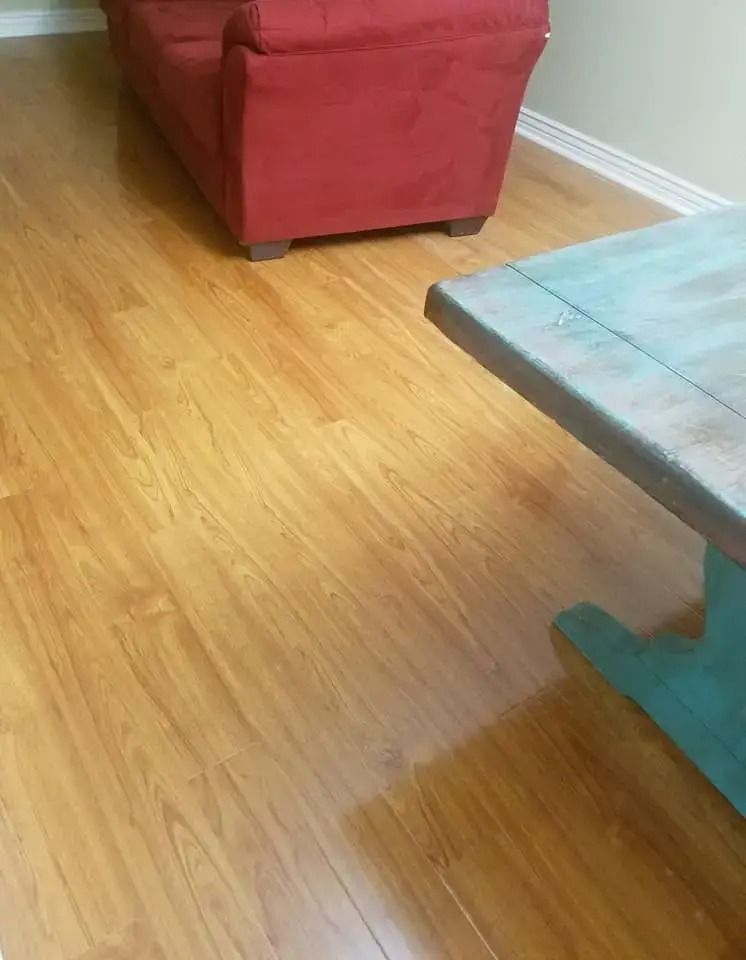 Living room with hardwood floor, red ottoman, and light blue coffee table edge