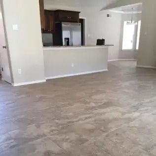 Empty open-plan living area with gray flooring, white walls, and a kitchen pass-through counter